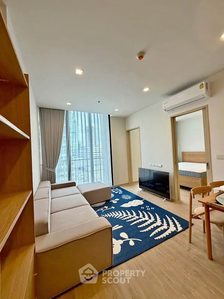 Modern living room with large windows and stylish furniture in a high-rise apartment.