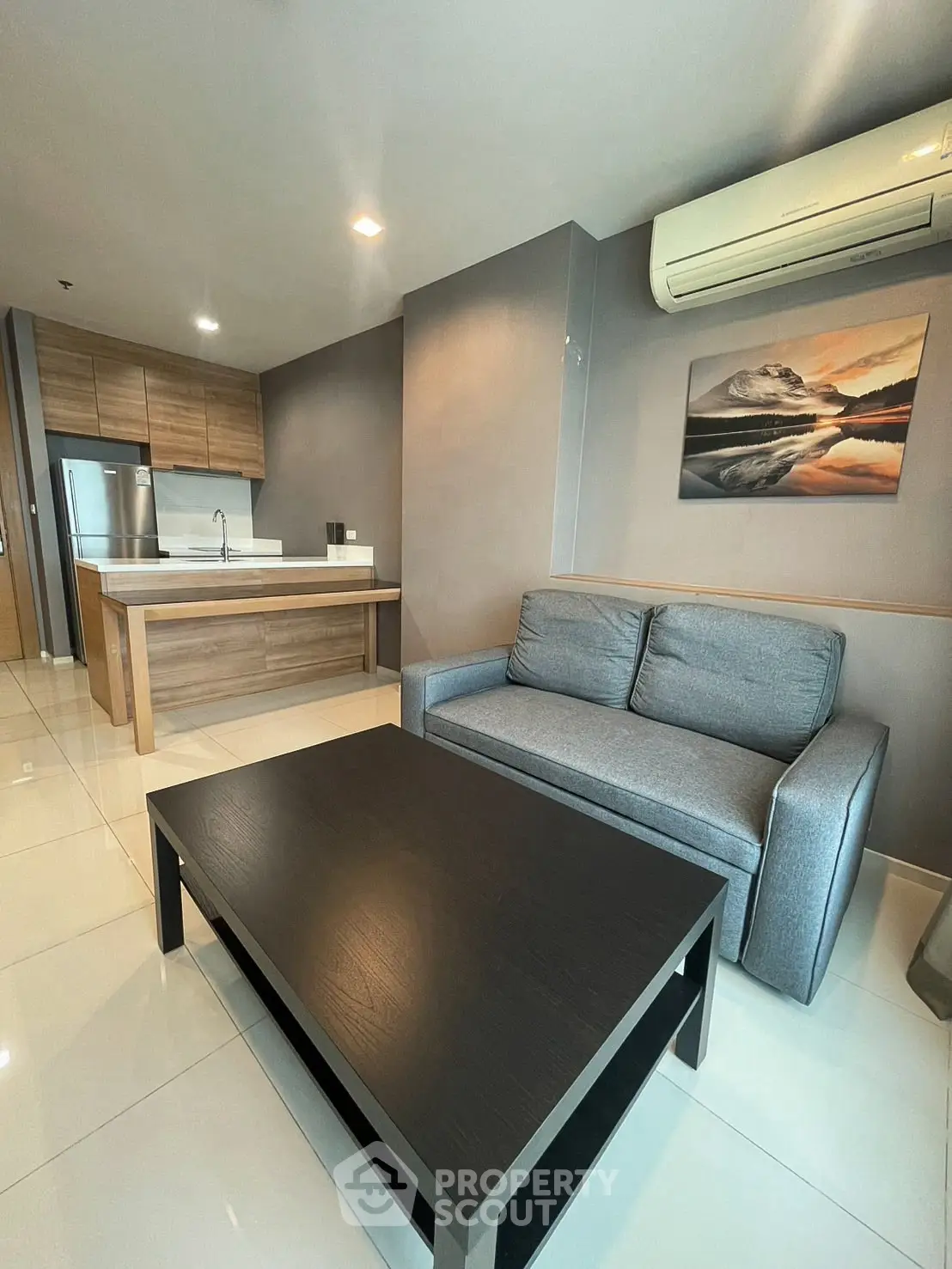 Modern living room with sleek kitchen, cozy sofa, and air conditioning in a stylish apartment.