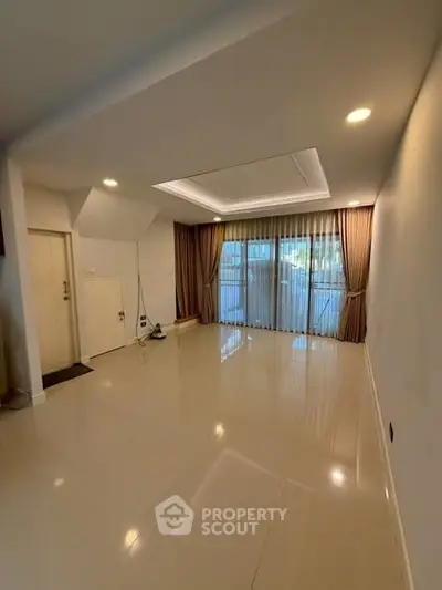 Spacious living room with elegant curtains and recessed lighting, perfect for modern living.