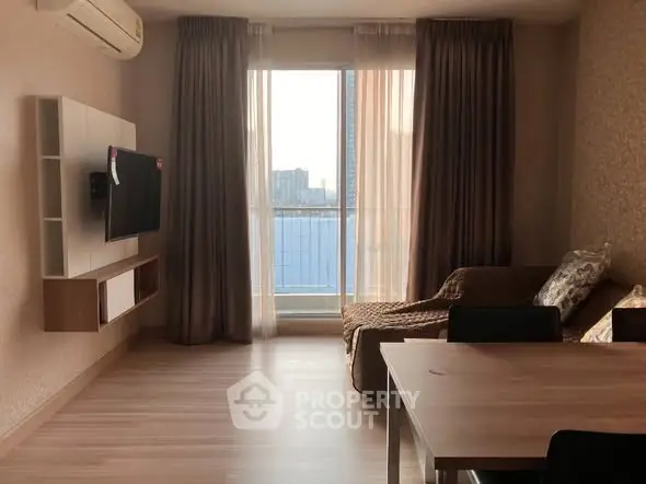 Spacious living room with modern decor and large window offering city view.
