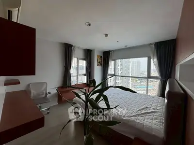 Spacious bedroom with large windows offering stunning city views, modern furnishings, and natural light.