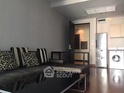 Modern living room with stylish sofa and integrated kitchen appliances in a sleek apartment.