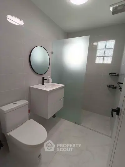 Modern bathroom with sleek fixtures and frosted glass shower in a stylish real estate property.