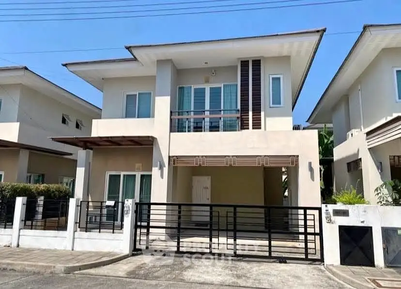 Modern two-story house with sleek design and gated entrance in a suburban neighborhood.
