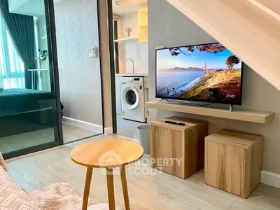 Modern living room with TV, washing machine, and cozy decor in stylish apartment.