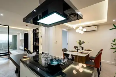 Modern kitchen with open layout and dining area, featuring sleek appliances and elegant lighting.