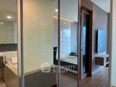 Modern apartment interior with glass partition, showcasing a sleek bedroom and bathroom design.