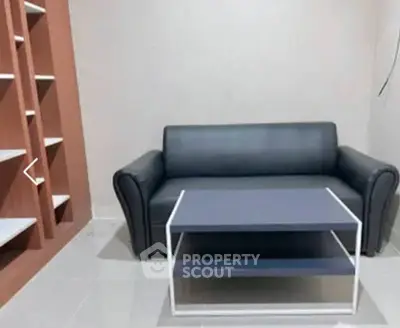 Modern living room with sleek black sofa and stylish coffee table, perfect for urban living.