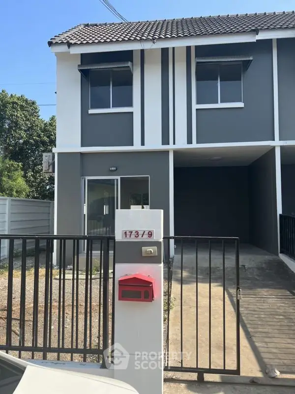 Modern townhouse exterior with gated driveway and mailbox, perfect for family living.