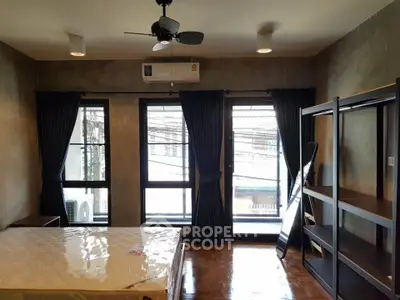 Spacious bedroom with large windows and modern furnishings in urban apartment.