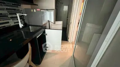 Compact kitchen with sleek black countertop and open fridge in modern apartment