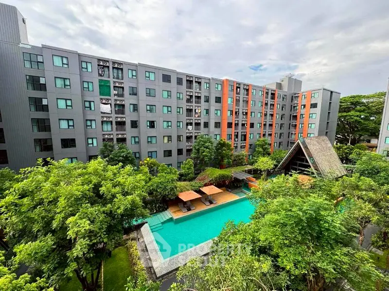 Modern apartment complex with lush greenery and inviting swimming pool view.