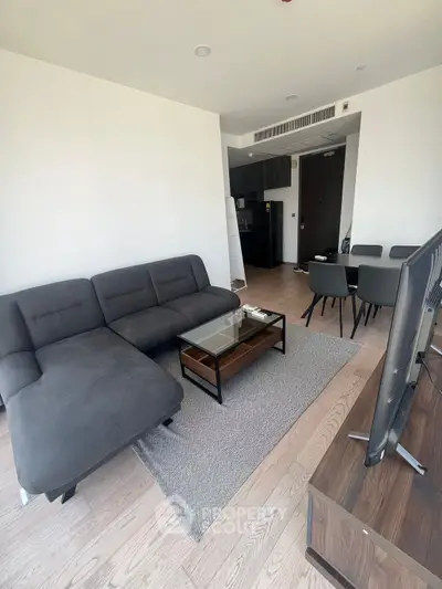 Modern living room with sleek furniture and open layout, featuring a cozy sectional sofa and dining area.