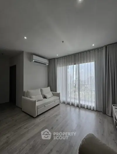 Spacious living room with modern decor and large window offering natural light.