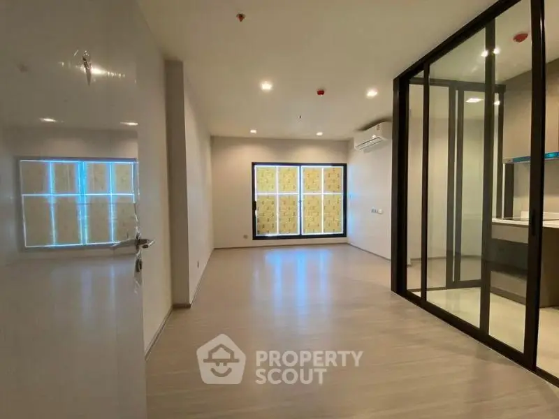 Spacious modern living room with glass partition and sleek flooring.