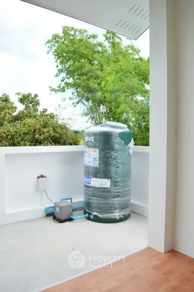 Spacious balcony with water tank and lush greenery view