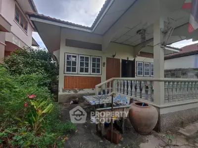 Charming single-story home with front porch and lush garden, ideal for cozy living.