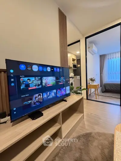 Modern living room with smart TV and view into cozy bedroom