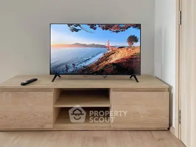 Modern living room with sleek wooden TV stand and flat-screen television, showcasing minimalist design.
