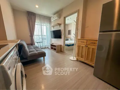 Modern living room with washing machine and fridge, open layout to bedroom, bright and airy space.