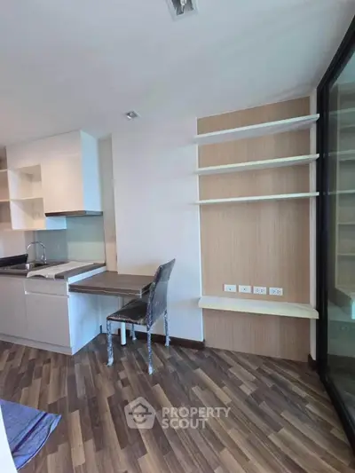 Modern kitchen with sleek cabinetry and integrated desk area, featuring stylish wood flooring.