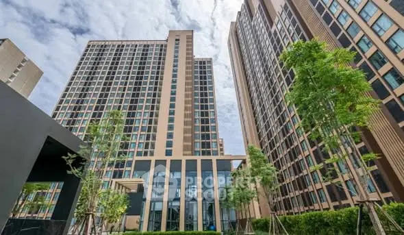 Modern high-rise residential building with lush greenery and clear sky view.
