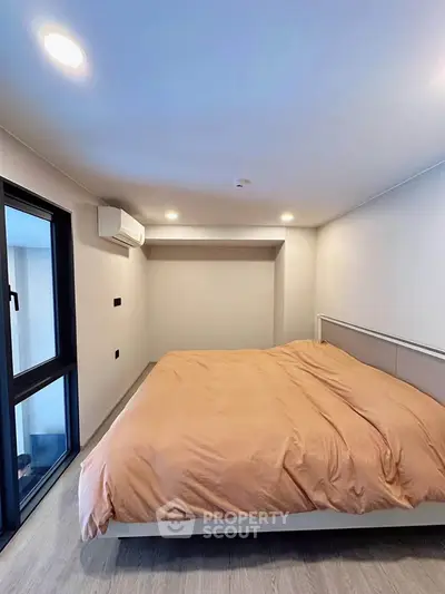 Modern bedroom with large window and cozy bedding in a stylish apartment.