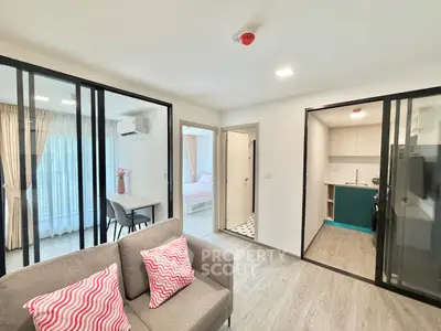Modern open-plan living room with glass partitions, cozy seating, and stylish kitchen in a contemporary apartment.