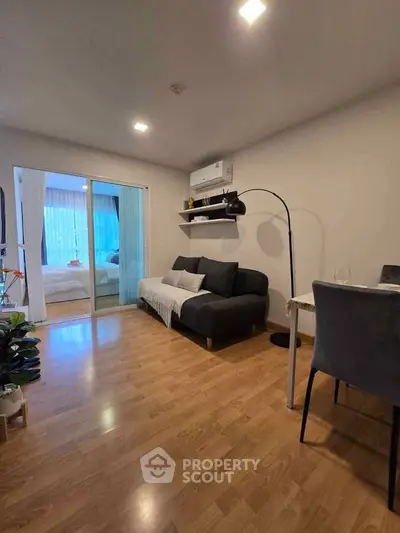 Modern living room with cozy sofa and dining area, featuring wooden flooring and bright lighting.