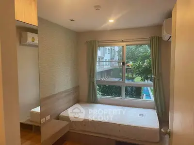 Cozy bedroom with large window overlooking lush greenery and pool, featuring modern air conditioning.