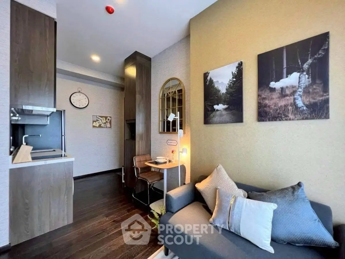 Modern living room with cozy sofa and stylish decor adjacent to compact kitchen area.