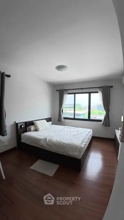 Cozy bedroom with large window and modern furnishings in a bright apartment.
