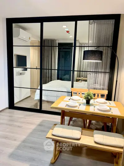 Modern studio apartment with glass partition, cozy dining area, and stylish decor.