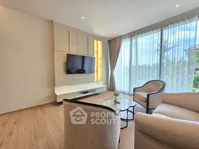 Elegant living room with modern furniture and large windows offering natural light and garden view.