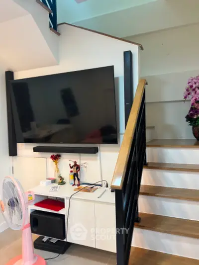 Modern living room with sleek staircase and large TV setup