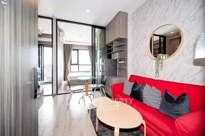 Modern living room with red sofa, stylish decor, and open layout leading to dining area with natural light.
