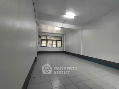 Spacious empty room with tiled flooring and large window, ideal for customization.