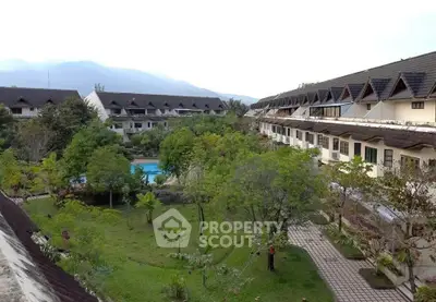 Charming residential complex with lush gardens and pool, nestled against scenic mountain backdrop.