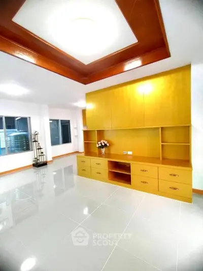 Spacious modern living room with built-in wooden cabinets and glossy tile flooring.