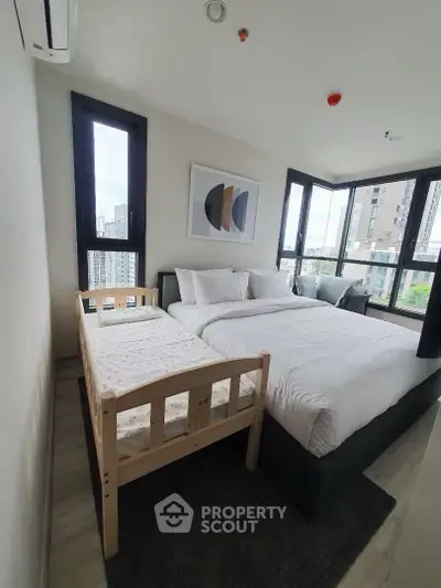 Modern bedroom with large windows and city view, featuring a cozy bed and stylish decor.