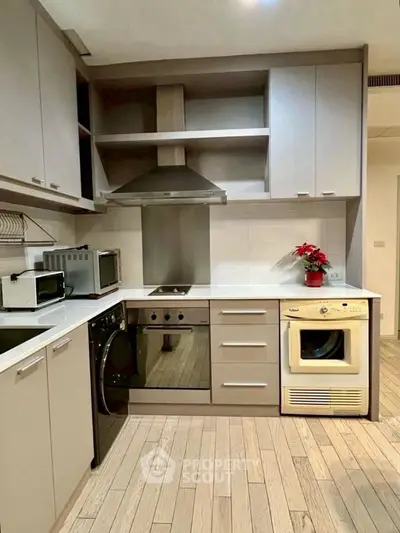 Modern kitchen with sleek cabinetry and appliances, featuring a washing machine and oven.