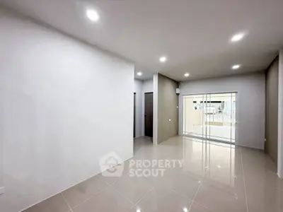 Spacious modern living room with sleek tile flooring and sliding glass doors leading to a balcony.