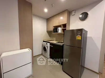 Modern compact kitchen with washing machine and stainless steel fridge in cozy apartment.
