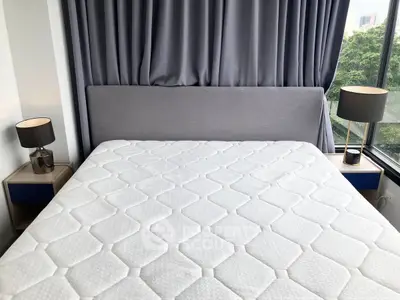 Modern bedroom with large bed and stylish lamps, featuring floor-to-ceiling windows with lush greenery view.