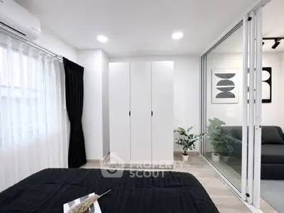 Modern bedroom with sleek wardrobe and glass partition, featuring minimalist decor and natural light.