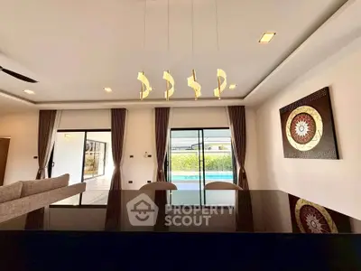 Luxurious living room with modern decor and pool view, featuring elegant lighting and stylish artwork.