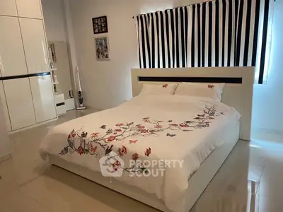 Spacious bedroom with elegant floral bedding and modern white furniture.