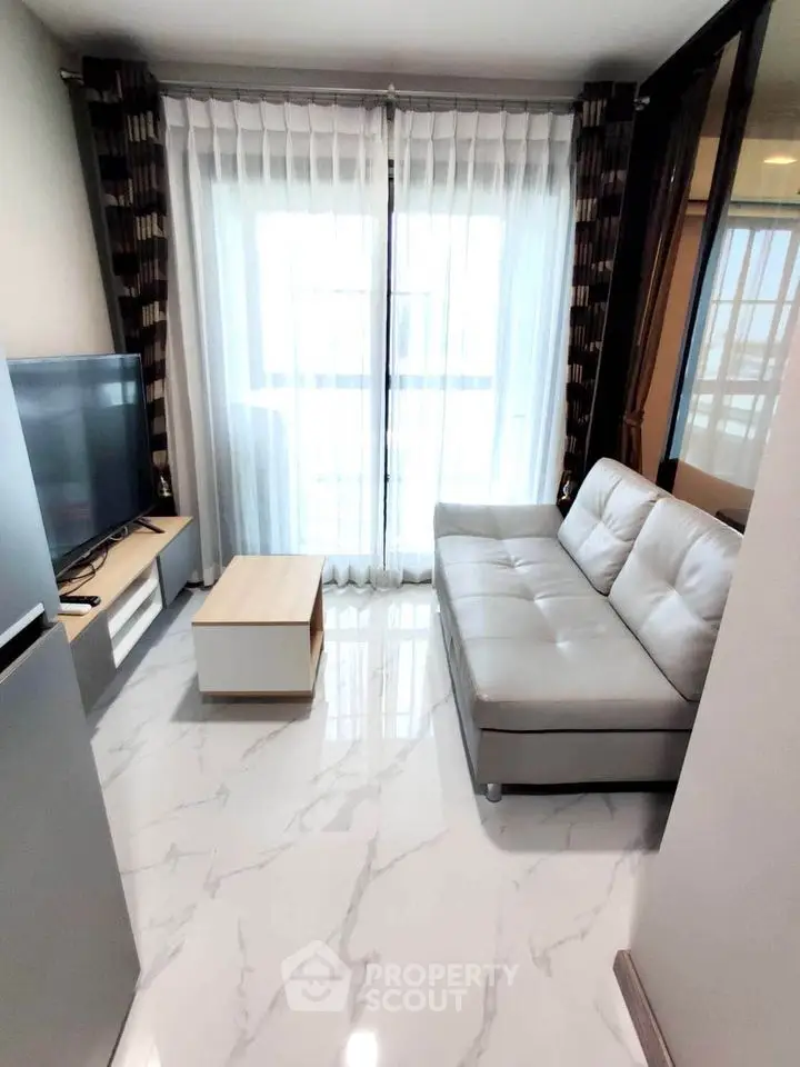 Modern living room with sleek sofa and large TV in bright apartment