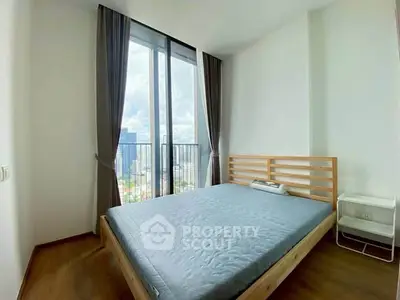 Spacious bedroom with large window offering stunning city views in modern apartment.