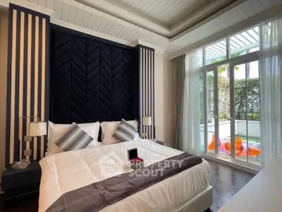 Luxurious bedroom with elegant decor and large windows opening to a private balcony with pool view.